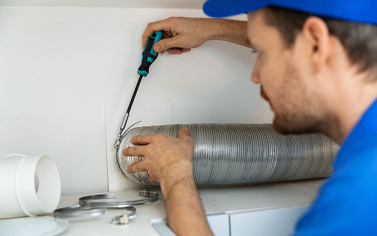 Contractor working on home ventilation, installing a new kitchen hood.