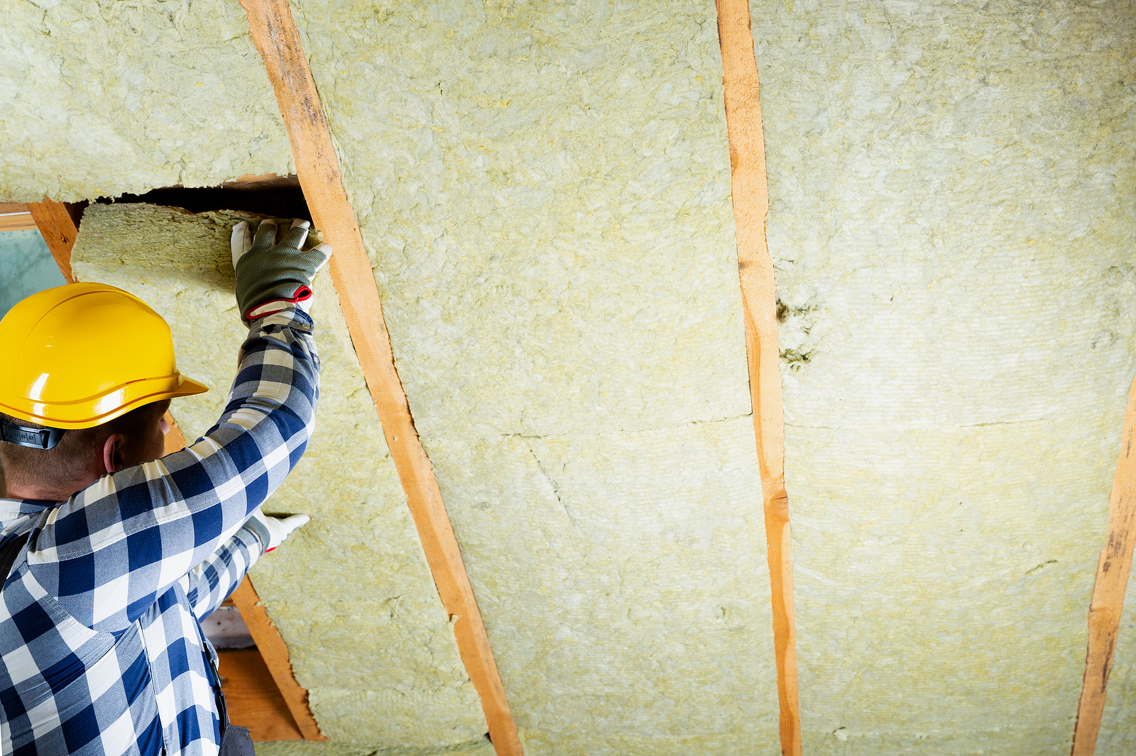 Contractor installing insulation in an attic space.