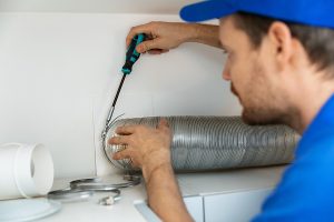Worker Installing Flexible Aluminum Ventilation Tube For Kitchen.