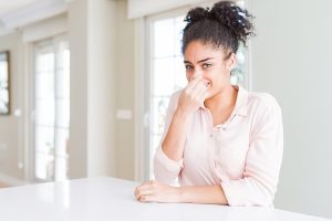 Woman holding her nose inside her house.