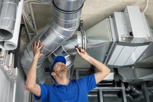 Technician inspecting and replacing air duct after cleaning.