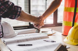 Construction contractor and homeowner shaking hands over renovation project.