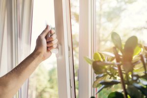 Hand of homeowner opening house window as part of house burping.