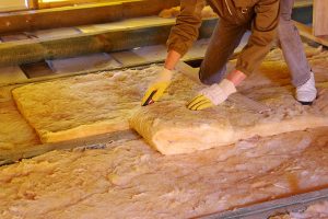 Worker installing insulation in an unfinished attic.
