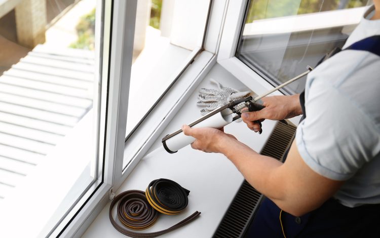 Construction Worker Sealing Window With Caulk Indoors